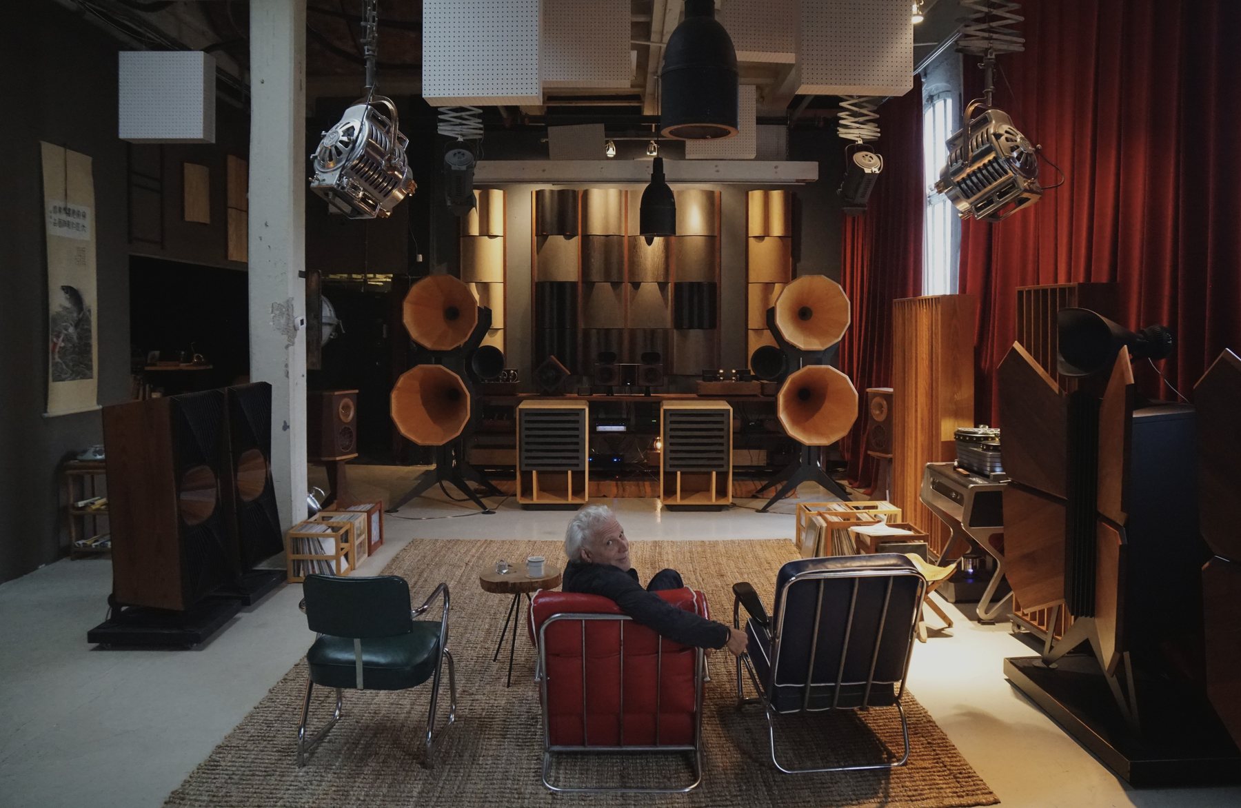Jonathan Weiss in a red armchair in his Dumbo listening loft